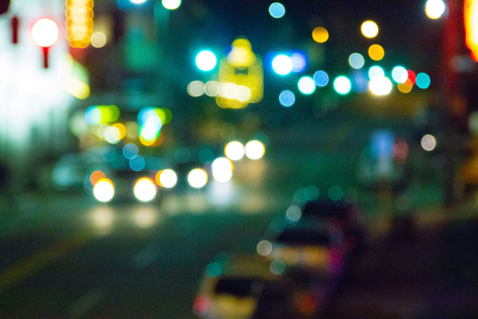 Defocused night city street with blurred, colorful bokeh lights
