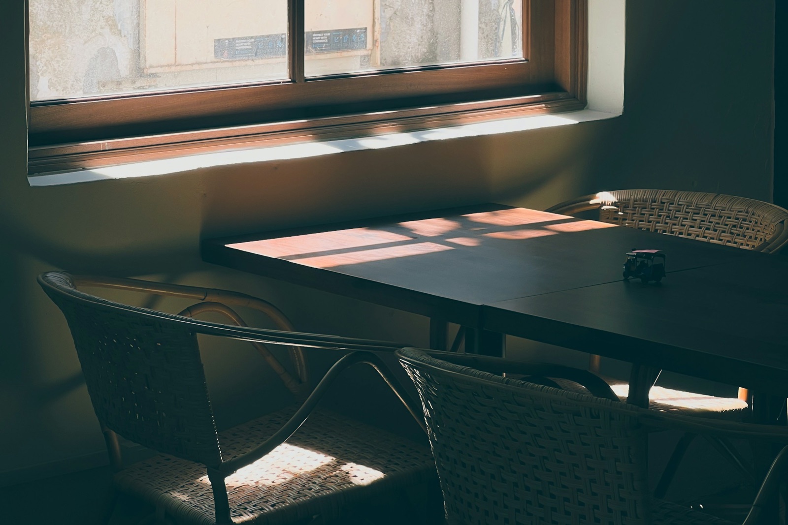 A kitchen table with two wicker chairs under a window, morning light across the tabletop
